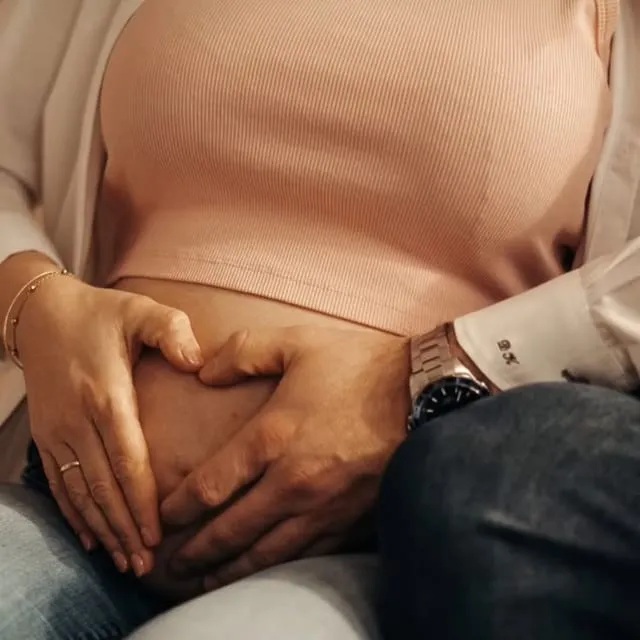 Zwei Hände liegen auf einem Babybauch.